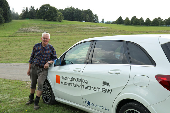Sommertour Kretschmann wandert mit Bürgerinnen und Bürgern Ministerpräsident Winfried Kretschmann neben einem Elektrofahrzeug, mit dem er die Fahrstrecken zwischen den einzelnen Etappen zurücklegt