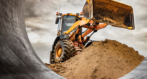 Powerful wheel loader or bulldozer working on a quarry or construction site. Loader with a full bucket of sand against the sky. Powerful modern equipment for earthworks.