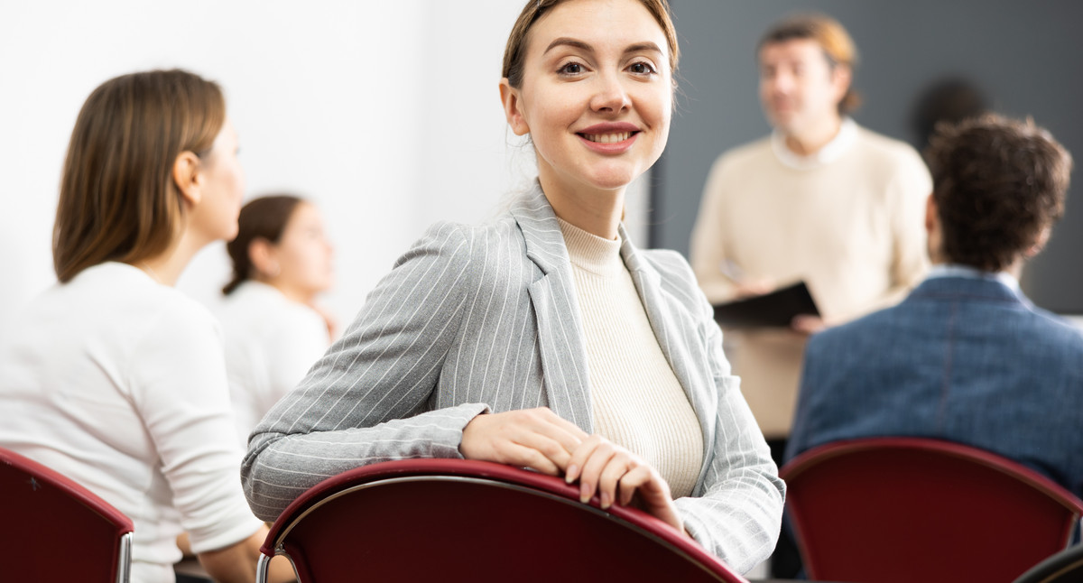 Young smiling female student sitting in college class