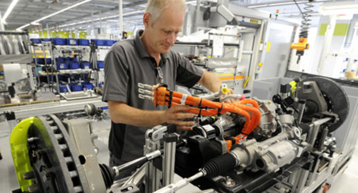 Ein Mitarbeiter montiert im Porsche Werk in Stuttgart-Zuffenhausen die Vorderachse mit Elektromotor (Bild: © dpa).