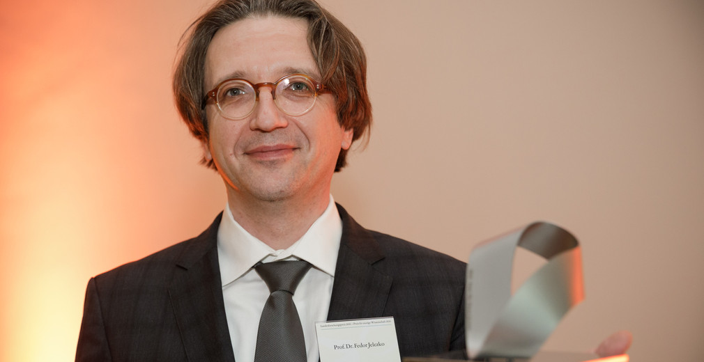 Prof. Fedor Jelezko mit dem in Form eines Möbiusbandes gestalteten Landesforschungspreis, Foto: MWK/Jan Potente