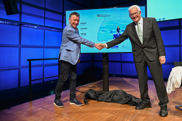Europa Erstes digitales deutsch-französisches Bürgerportal eröffnet Ministerpräsident Winfried Kretschmann (rechts) und der Präsident der Région Grand Est, Franck Leroy (links), geben sich vor einer Videowand mit dem neuen Bürgerportal die Hand.