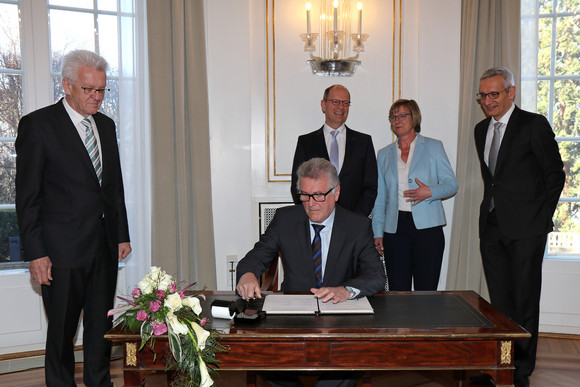 Besoldung Mehr Geld für Beamte Volker Stich (sitzend), Vorsitzender des Beamtenbundes Baden-Württemberg, unterzeichnet die Vereinbarung; stehend v.l.n.r.: Ministerpräsident Winfried Kretschmann, Matthias Grewe, Vorsitzender des Vereins der Richter und Staatsanwälte Baden-Württemberg e.V., Finanzministerin Edith Sitzmann und Staatssekretär Martin Jäger