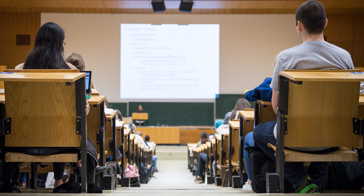 Studentinnen und Studenten sitzen während einer Vorlesung in einem Hörsaal. 