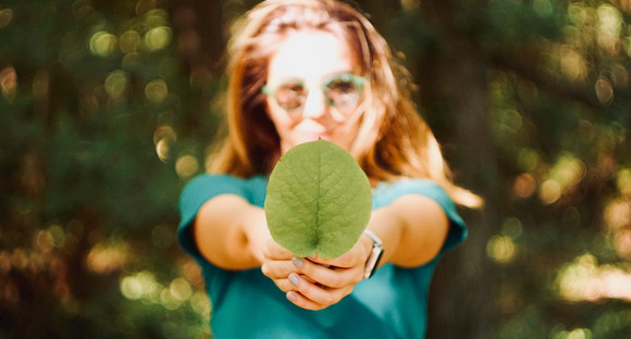 Frau hält ein grünes Blatt in der Hand
