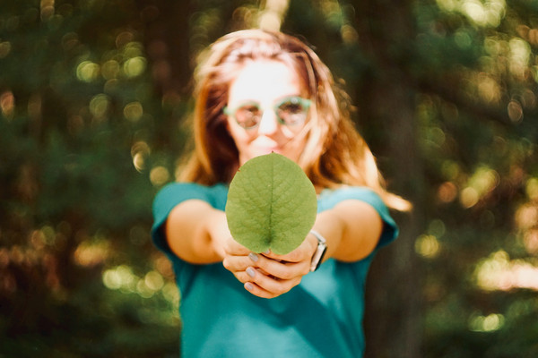 Frau hält ein grünes Blatt in der Hand