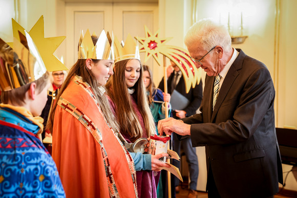 Aktion Dreikönigssingen Kretschmann empfängt Sternsingergruppen Ministerpräsident Winfried Kretschmann (rechts) überreicht den Sternsingerinnen und Sternsingern eine Geldspende.