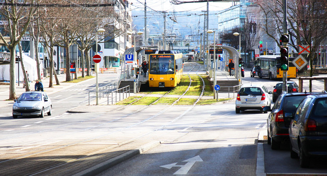 Eine Straßenszene in Stuttgart zeigt verschiedene Verkehrsmittel, wie Bus, U-Bahn, Auto und Fahrrad. (Bild: Staatsministerium Baden-Württemberg)']