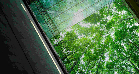 Eco-friendly building in modern city. Sustainable glass office building with trees for reducing carbon dioxide. Office building with green environment. Corporate building reduce CO2. Net zero emission