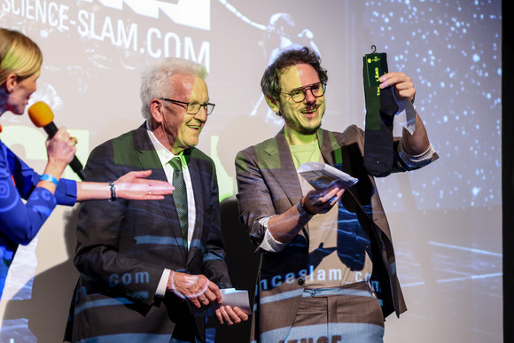 Zusammenhalt in der Transformation Tagung „Gemeinsam handeln“ Ministerpräsident Winfried Kretschmann (links) überreicht Moderator Rainer Holl, Science Slam, (rechts) „The Länd-Socken“ in der Alten Feuerwache in Mannheim.