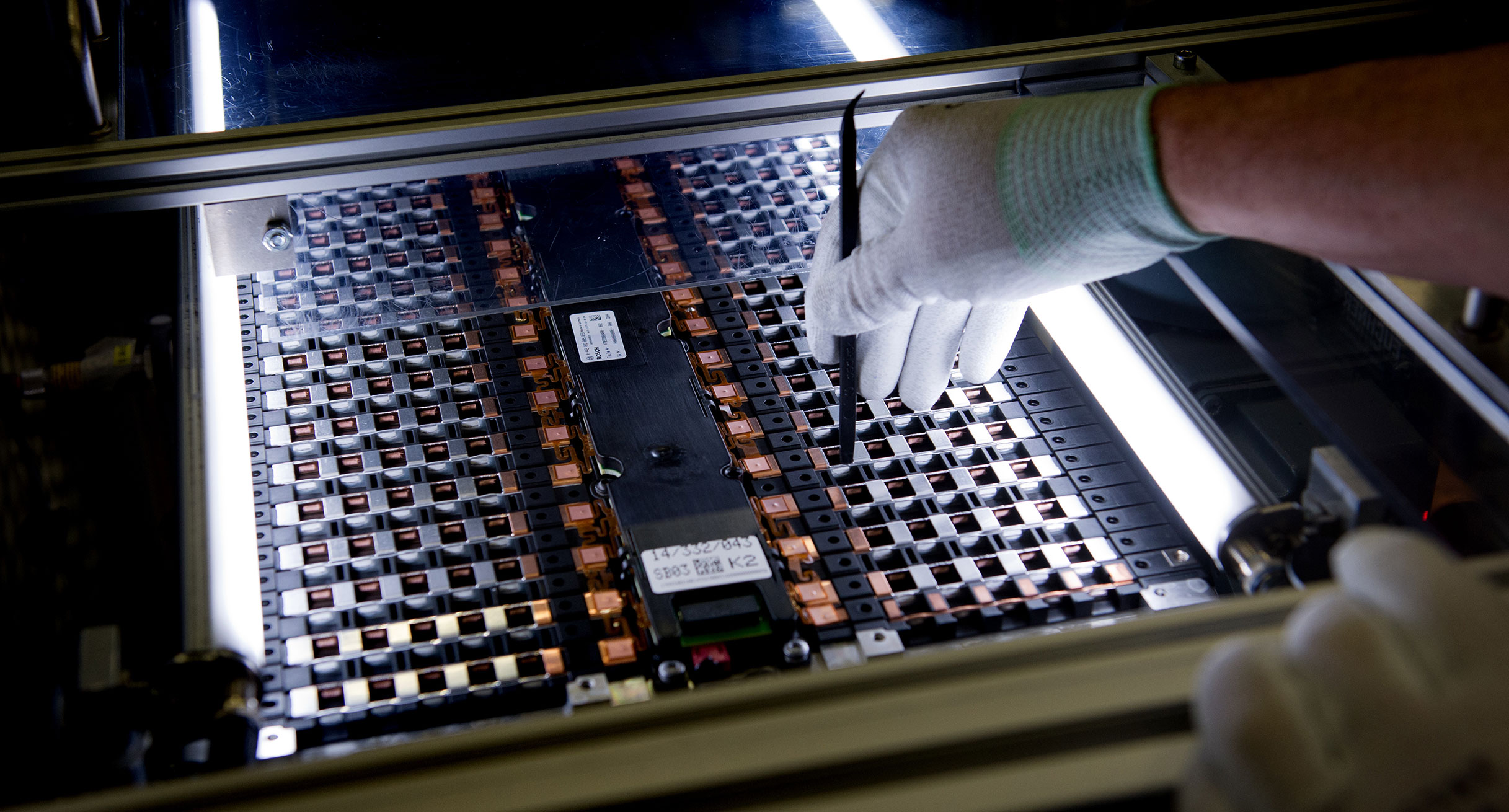 Ein Mitarbeiter arbeitet in der Produktion an einer Zelle für eine Elektroauto-Batterie. (Bild: dpa)']